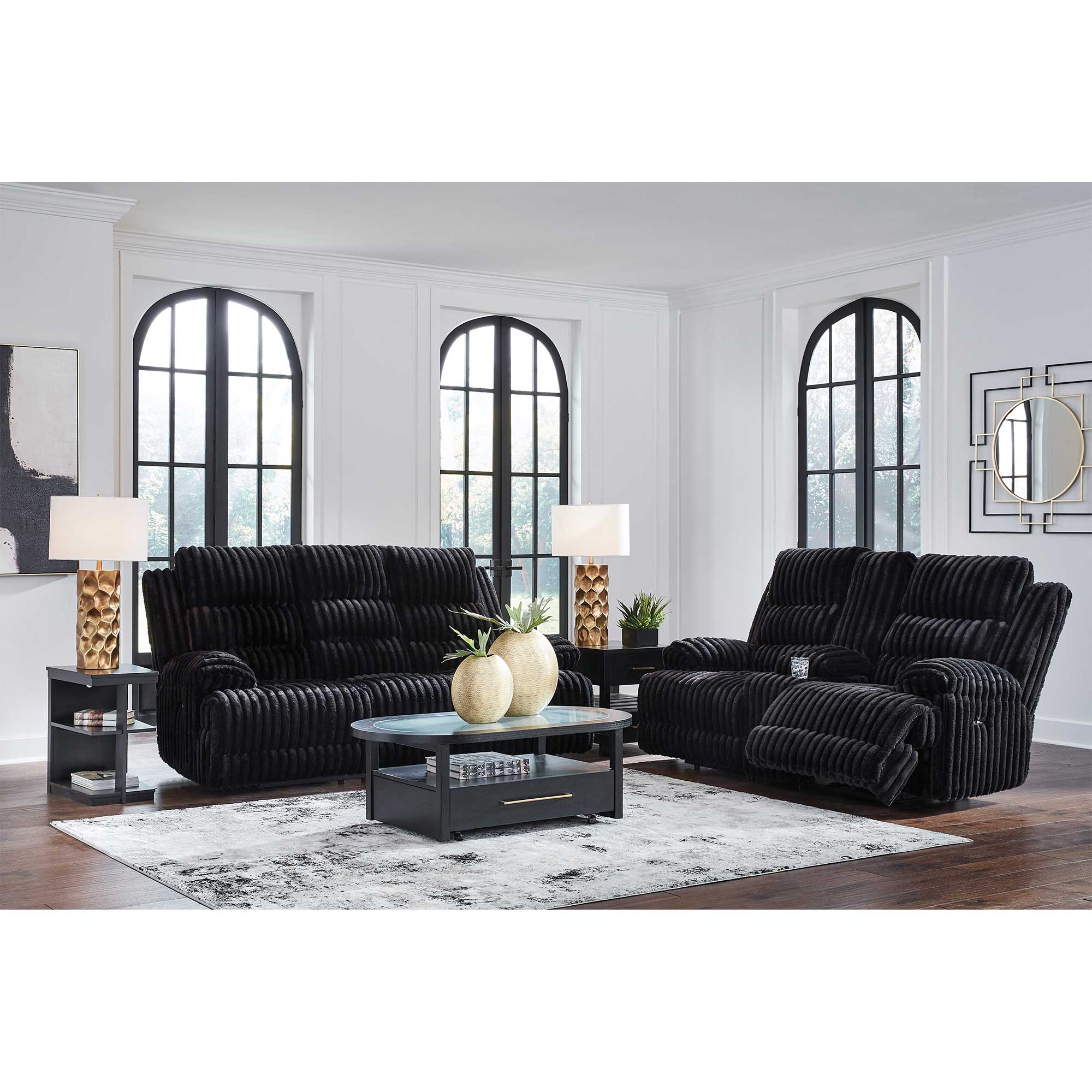 Black sofa set in a living room with large windows and decorative elements.
