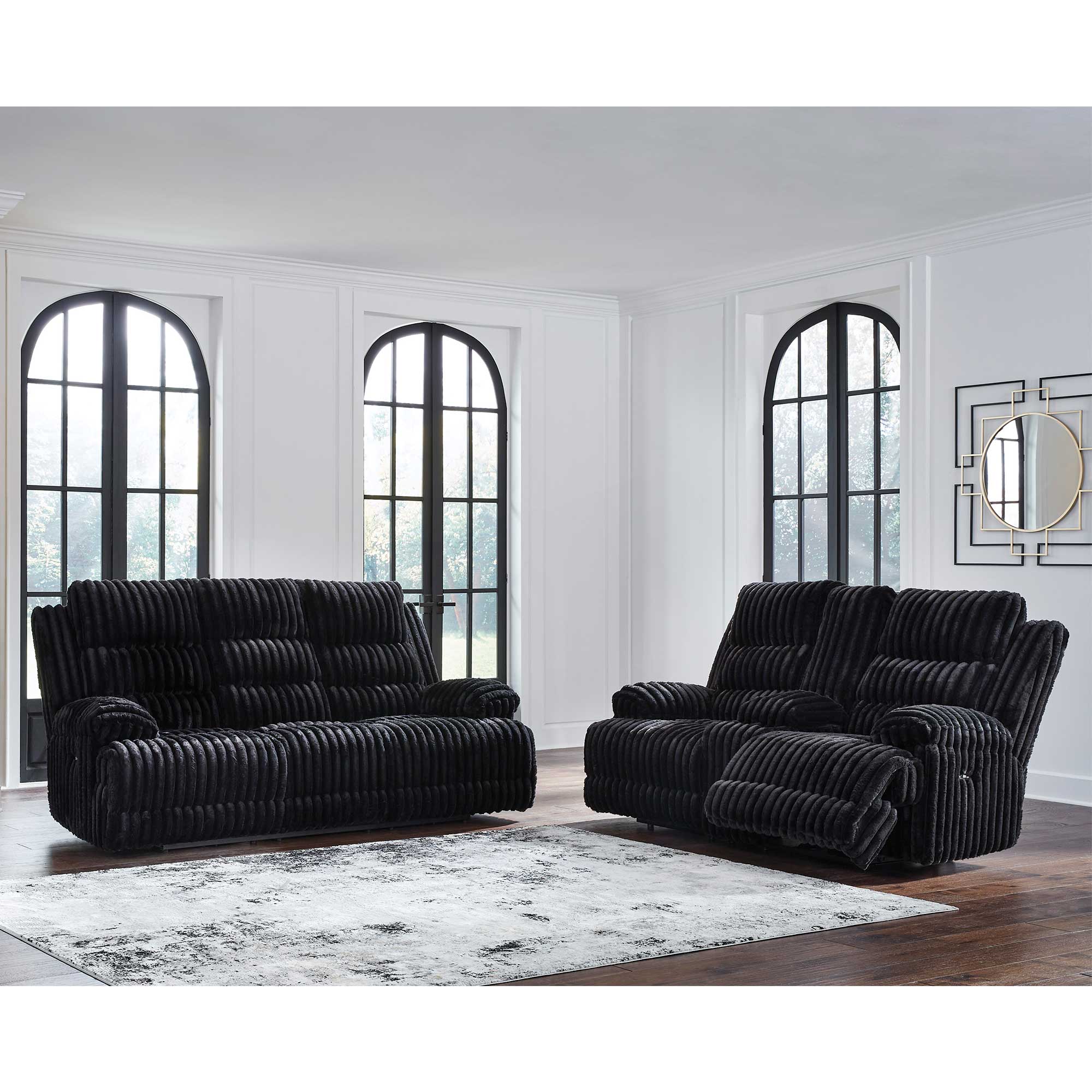 Black sofa set in a room with large windows and a rug.