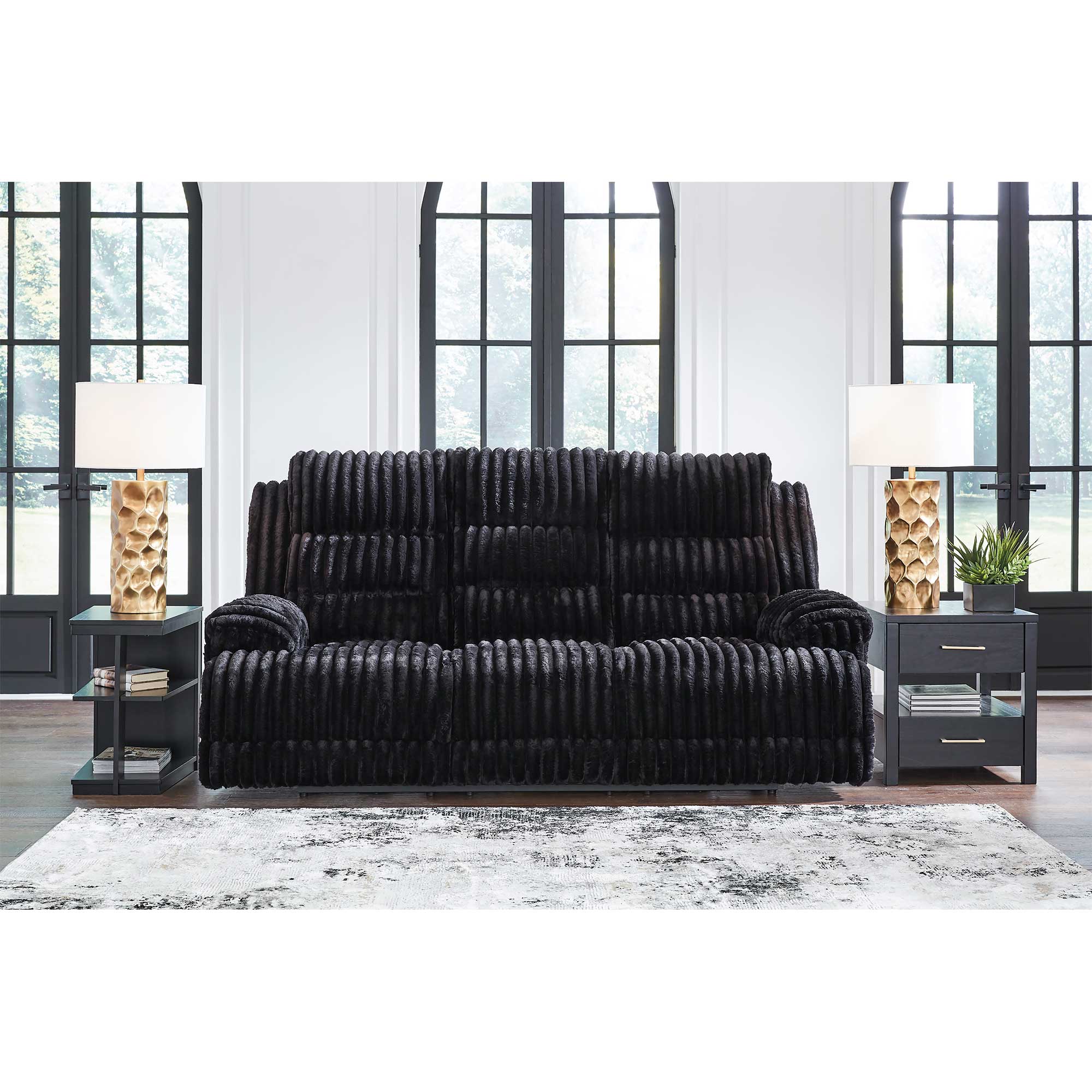Black sofa in a modern living room with large windows.