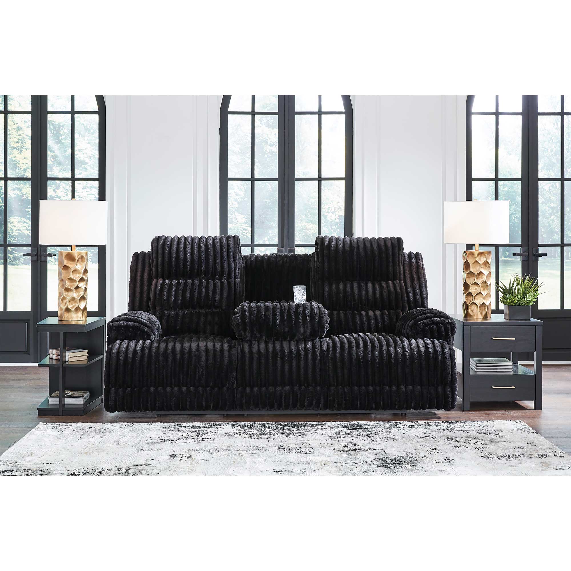 Black sofa set in a modern living room with large windows.